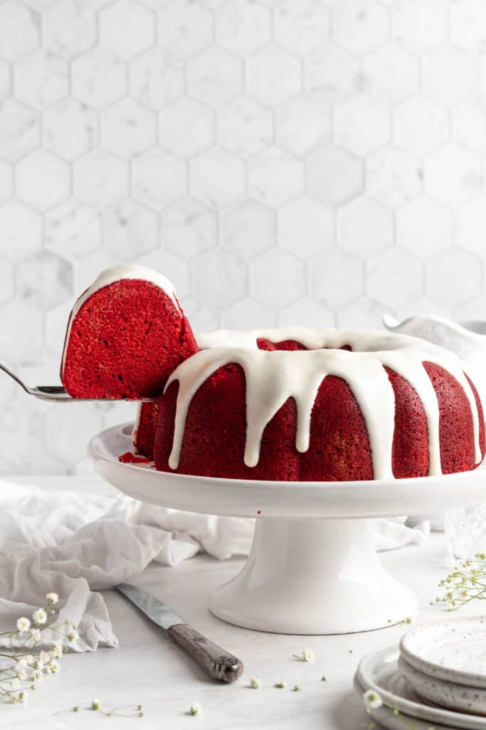 red velvet bundt cake on a cake pedestal with a slice taken out 
