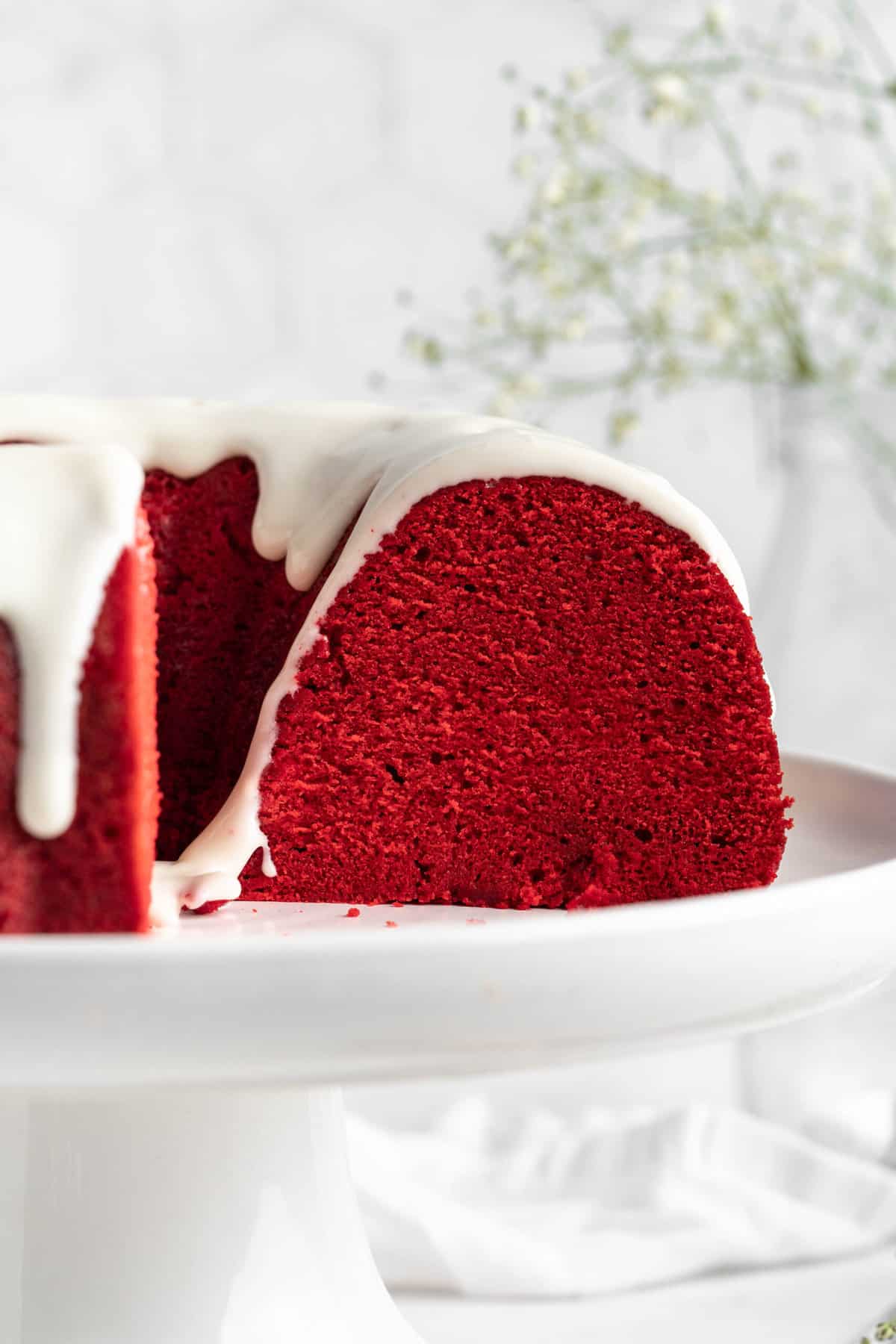 Cross section photo of red velvet bundt cake with cream cheese icing on a pedestal platter.