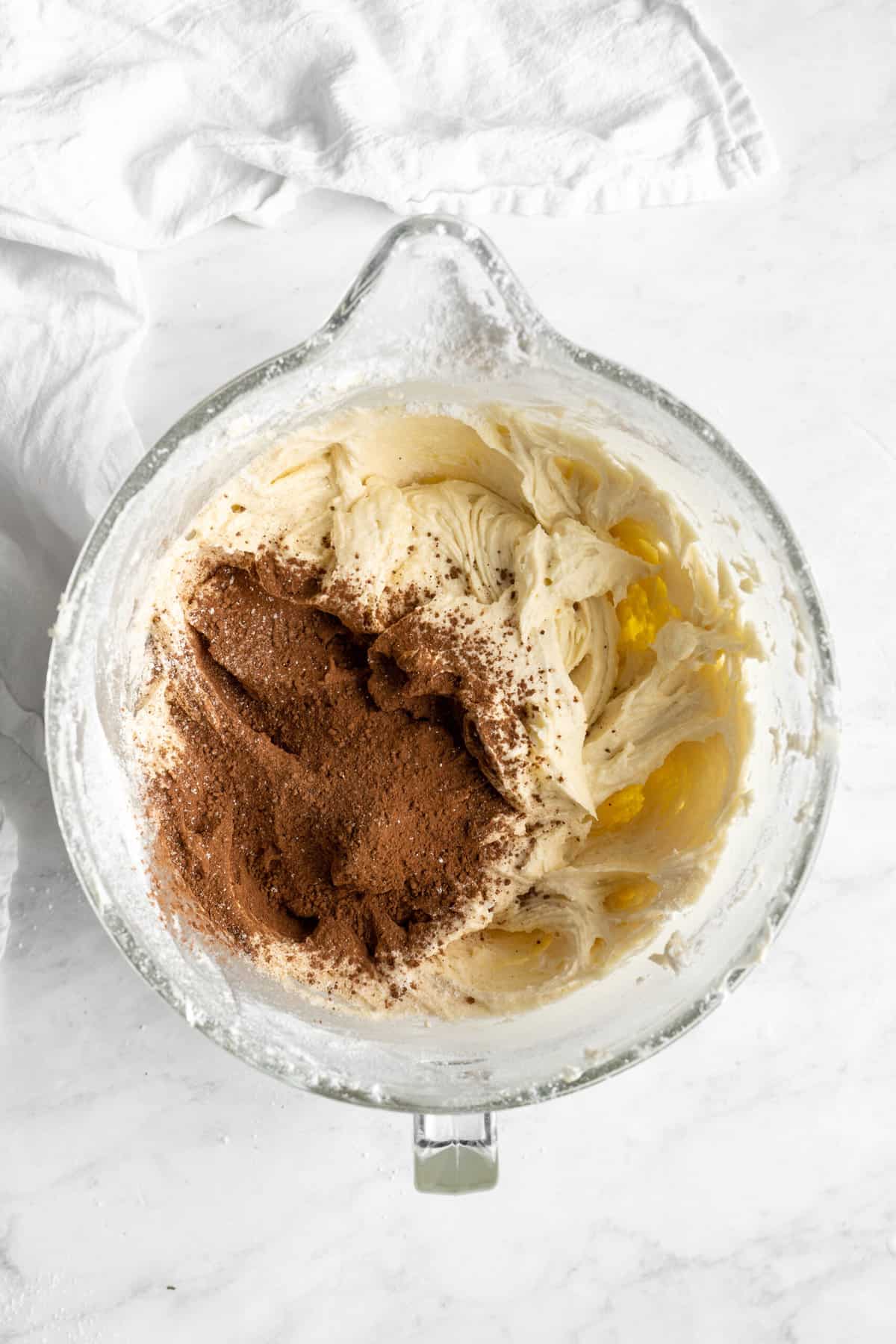 Cocoa powder added to stand mixer with cake batter on white countertop