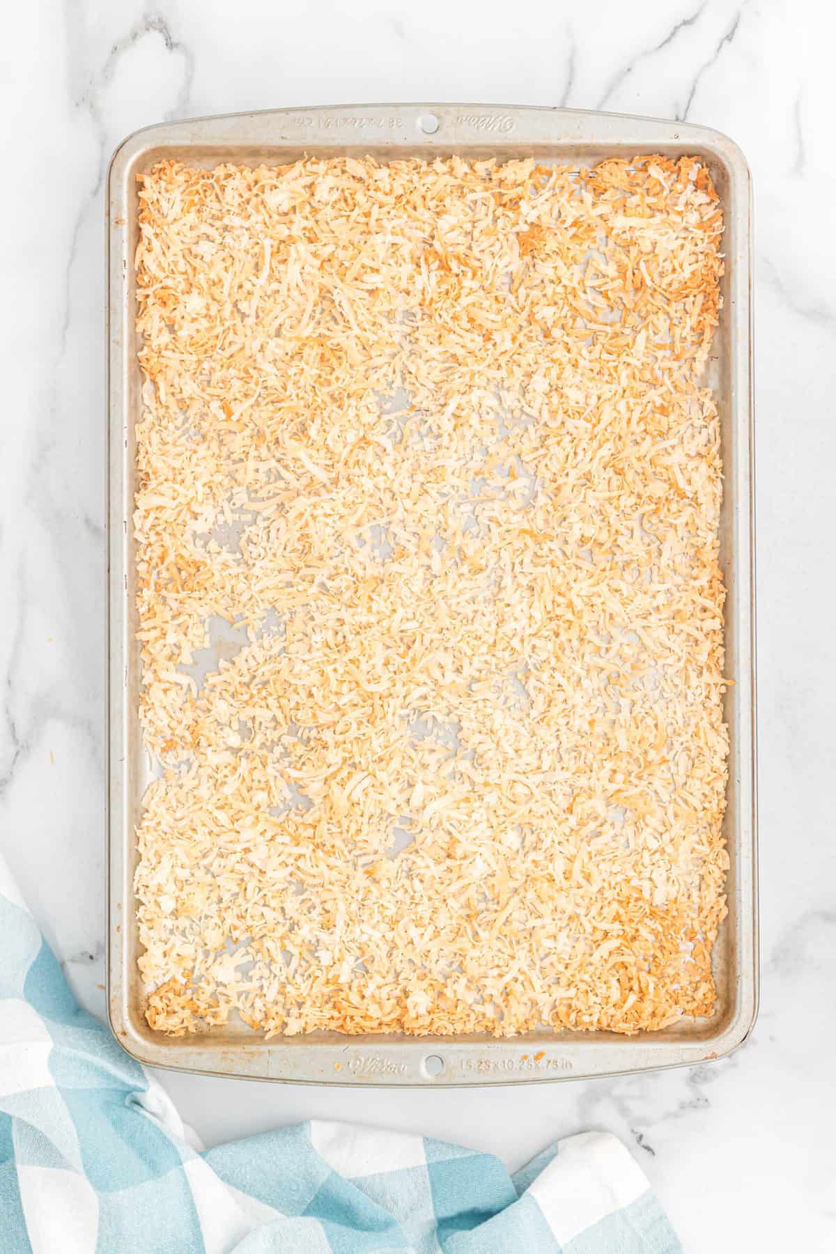 Toasted shredded coconut on a baking sheet.
