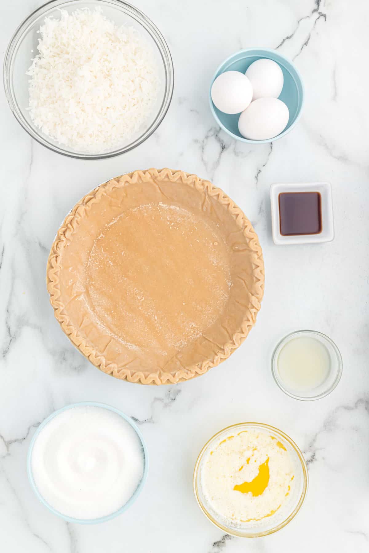 Ingredients to make toasted coconut pie on a white surface.