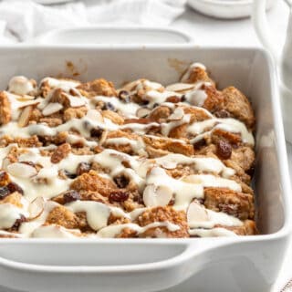 A white square baking dish of bread pudding with raisins.