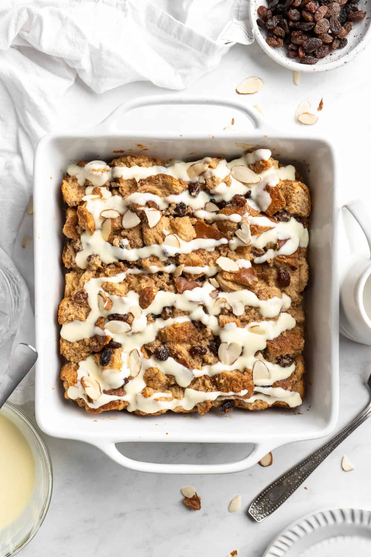 Bread pudding with cream sauce on white countertop before serving