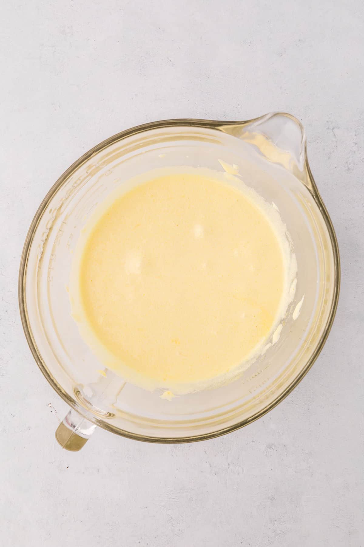 Eggs and sugar mixed in a stand mixer bowl on white countertop