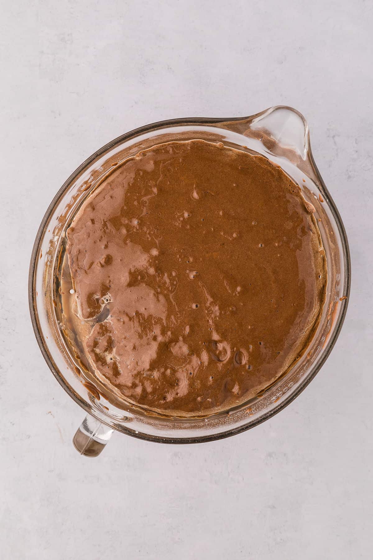 Chocolate cake batter being mixed in a stand mixer bowl on countertop