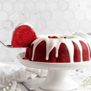 Red velvet bundt cake on a cake pedestal with a slice taken out