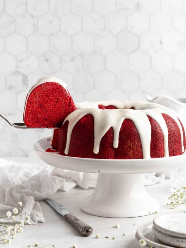 Red velvet bundt cake on a cake pedestal with a slice taken out