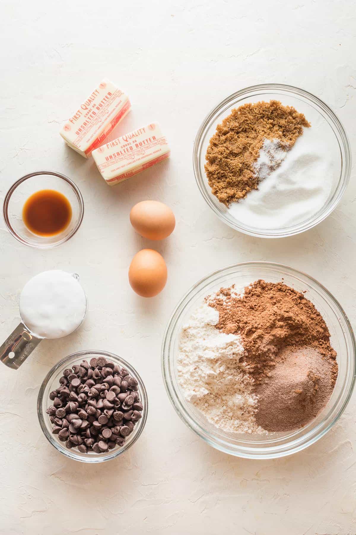 Ingredients to make hot chocolate cookies in small bowls on a counter.