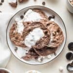 Hot chocolate cookies with marshmallow stacked on a white plate.