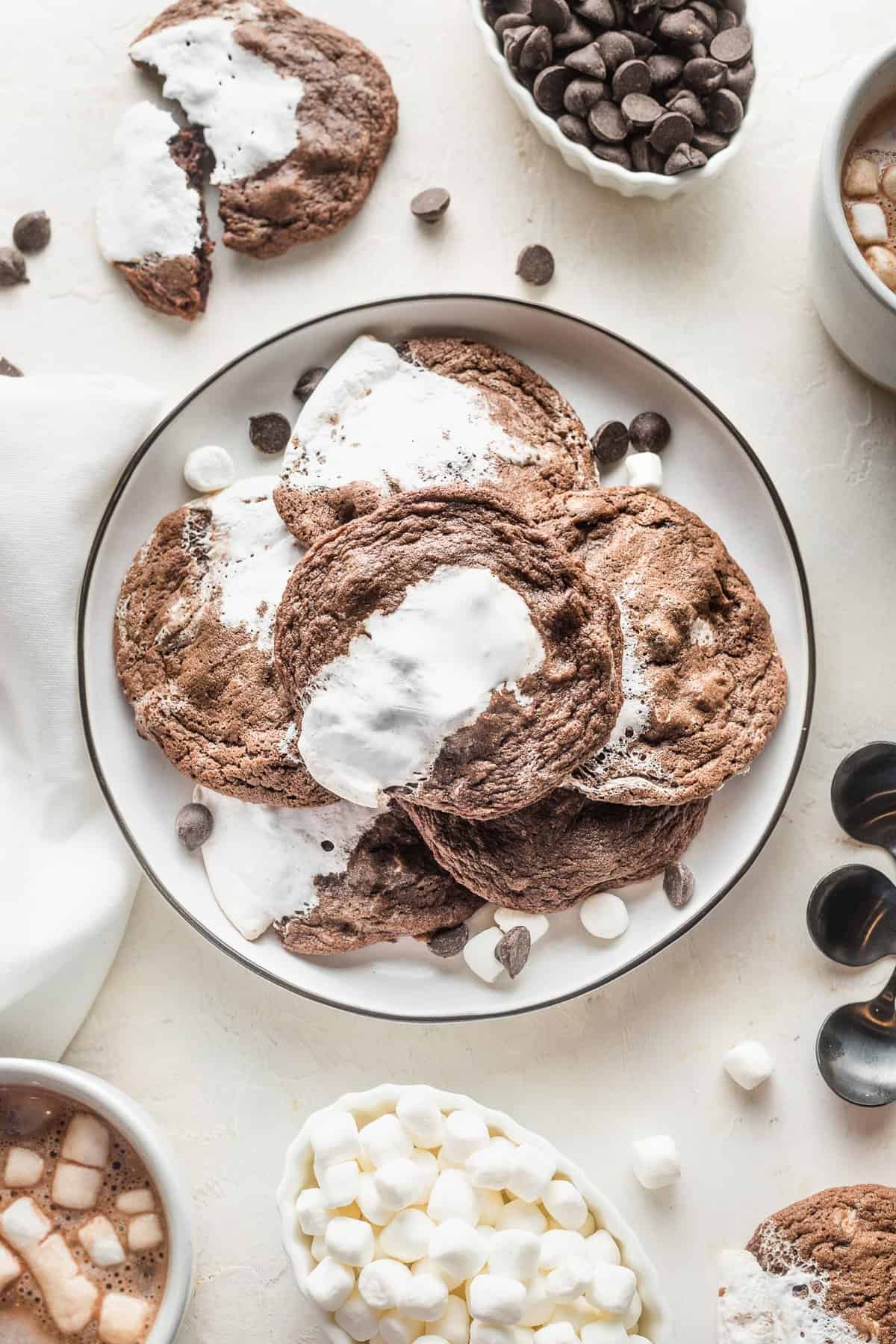 Hot chocolate cookies with marshmallow stacked on a white plate.