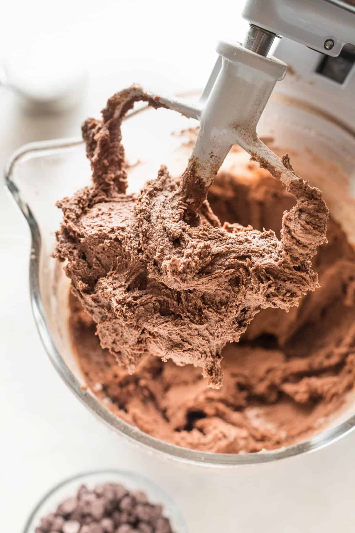 Chocolate cookie dough on the beater of a stand mixer.