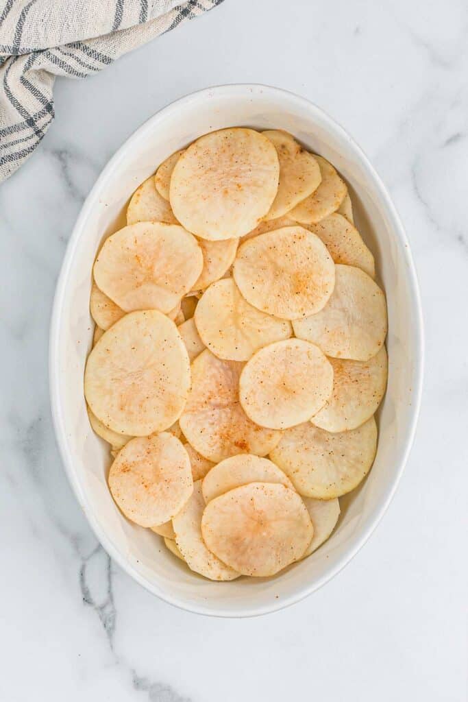 Potatoes layered into a casserole dish to make the best scalloped potatoes