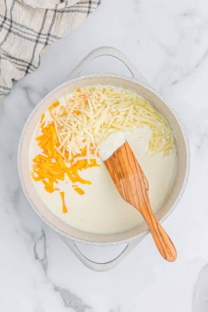 Dairy and cheese added to butter and flour mixture to make the cheesy sauce.