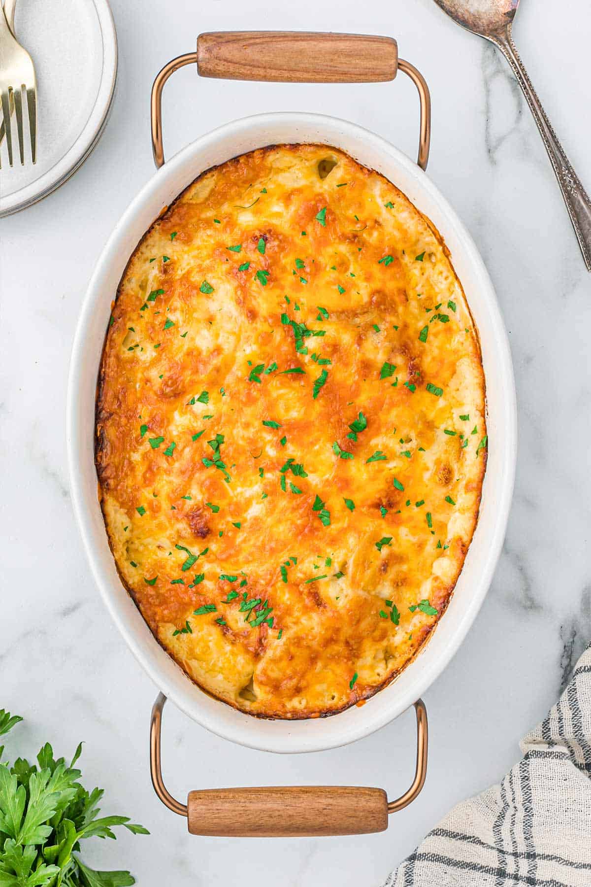 Cheesy scalloped potatoes in an oval casserole dish baked and ready to serve.