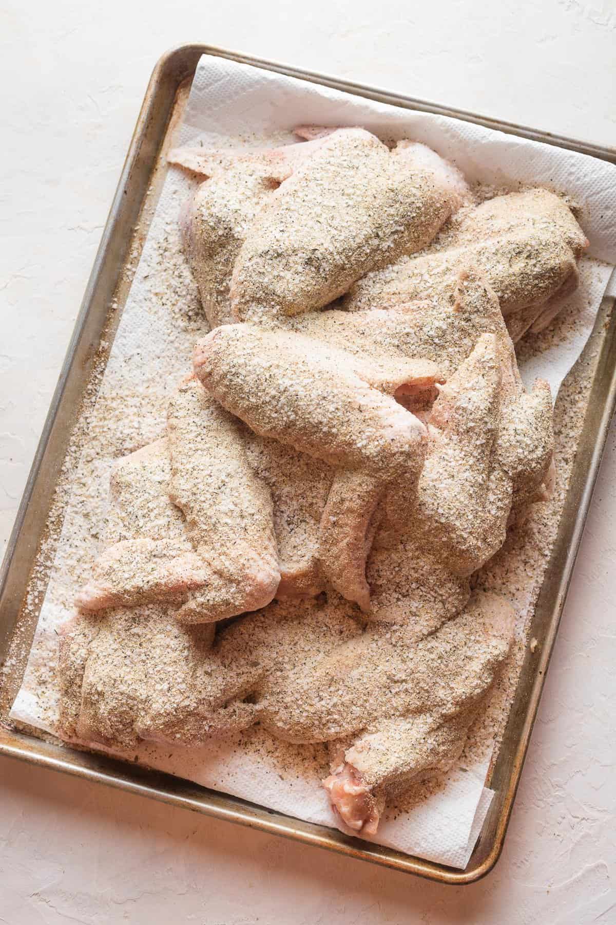 turkey wings liberally seasoned on a baking sheet