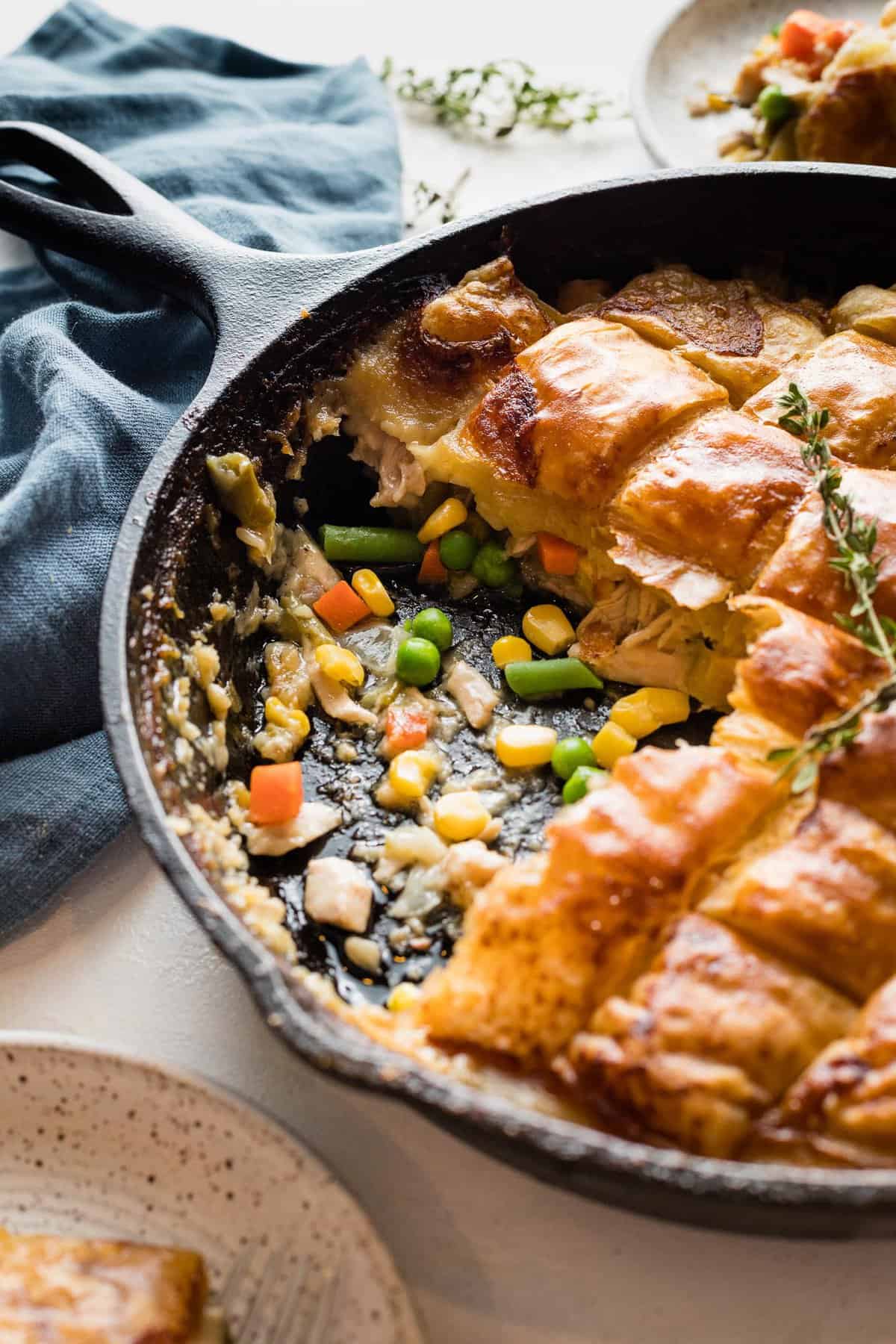 Turkey pot pie in a cast iron skillet with a serving missing.