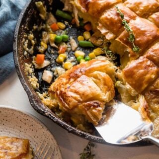 turkey pot pie with puff pastry in a cast iron skillet being scooped out