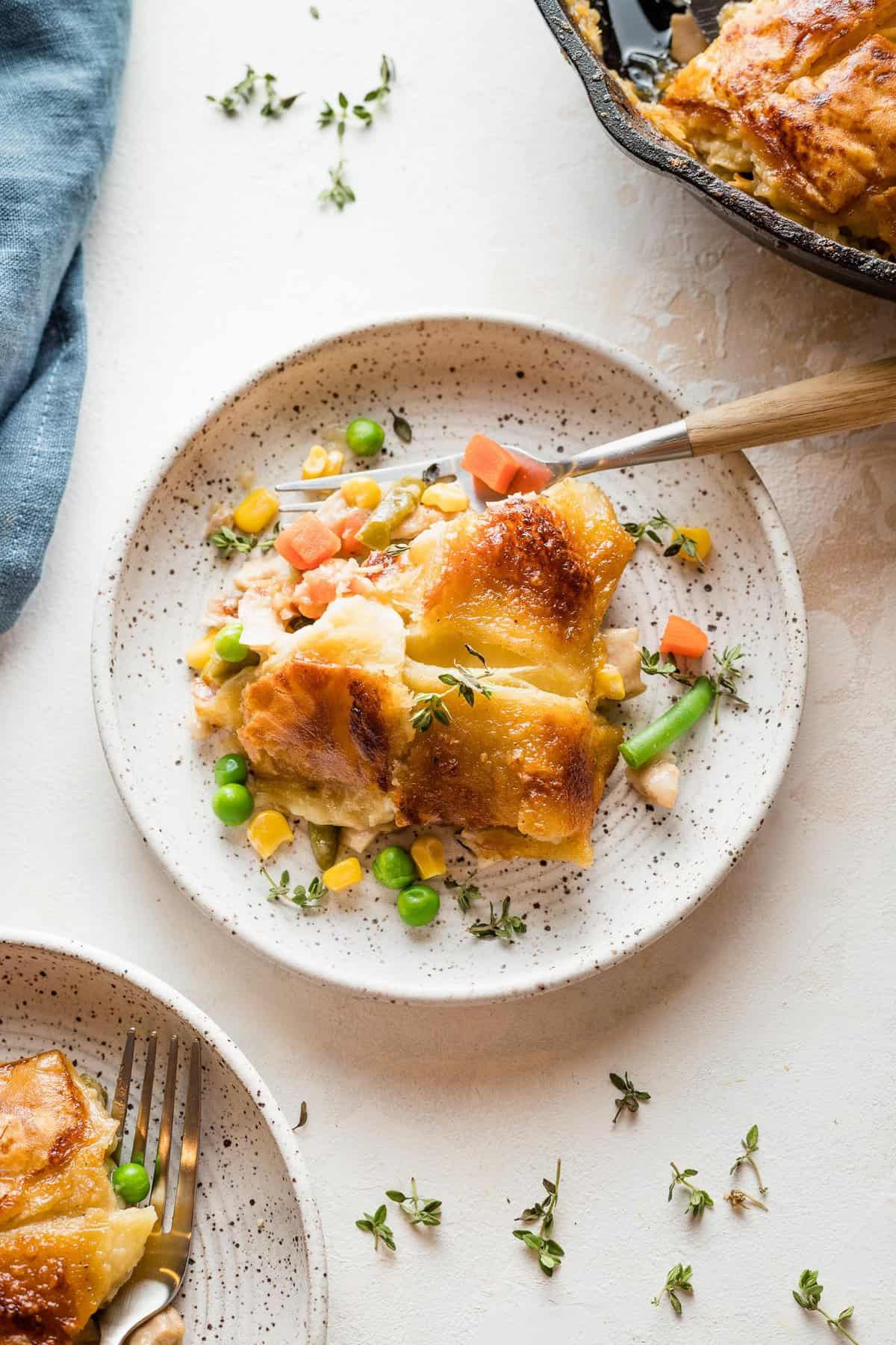 A serving of turkey pot pie with a fork on a small white plate.