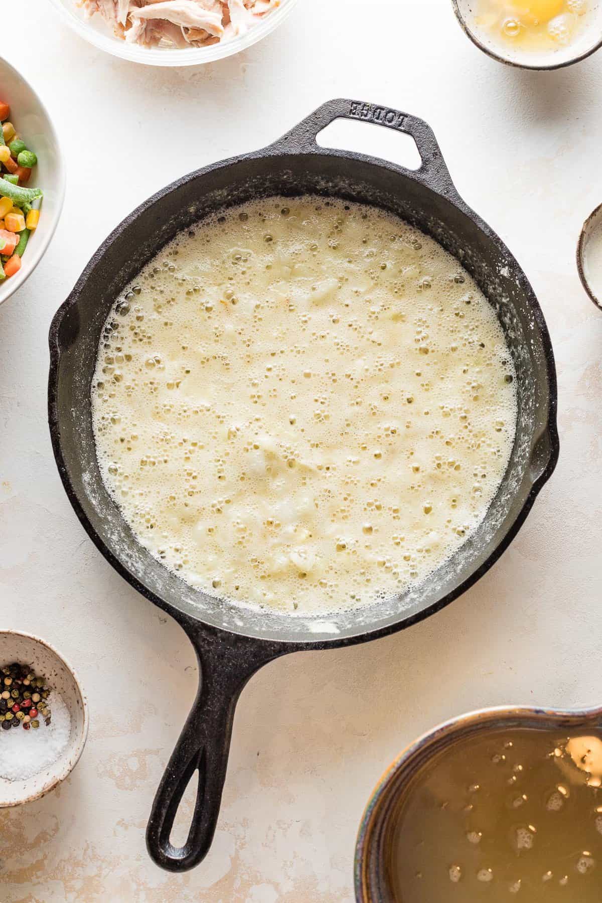 A bubbling gravy in a skillet for turkey pot pie filling.