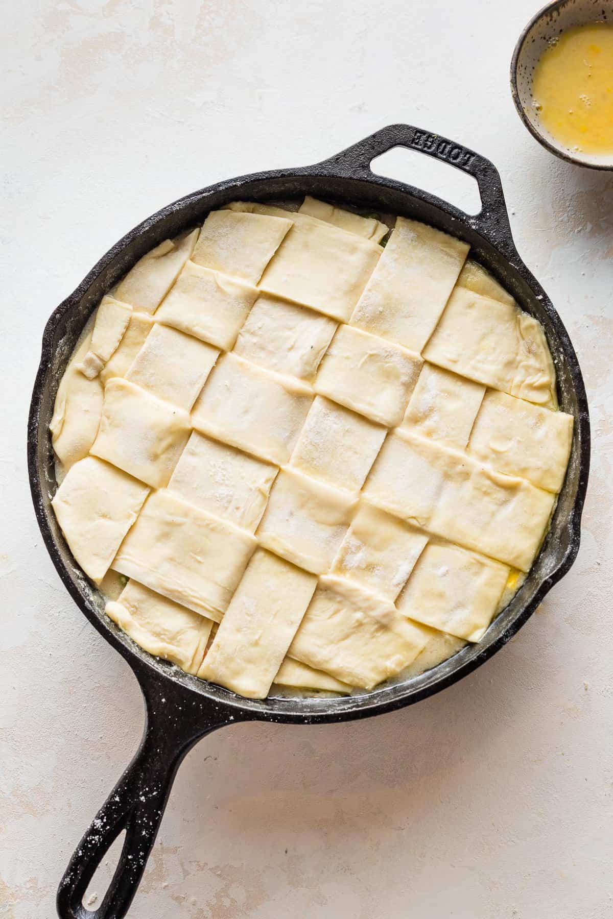 Lattice pastry crust over turkey pot pie filling in a cast iron skillet.