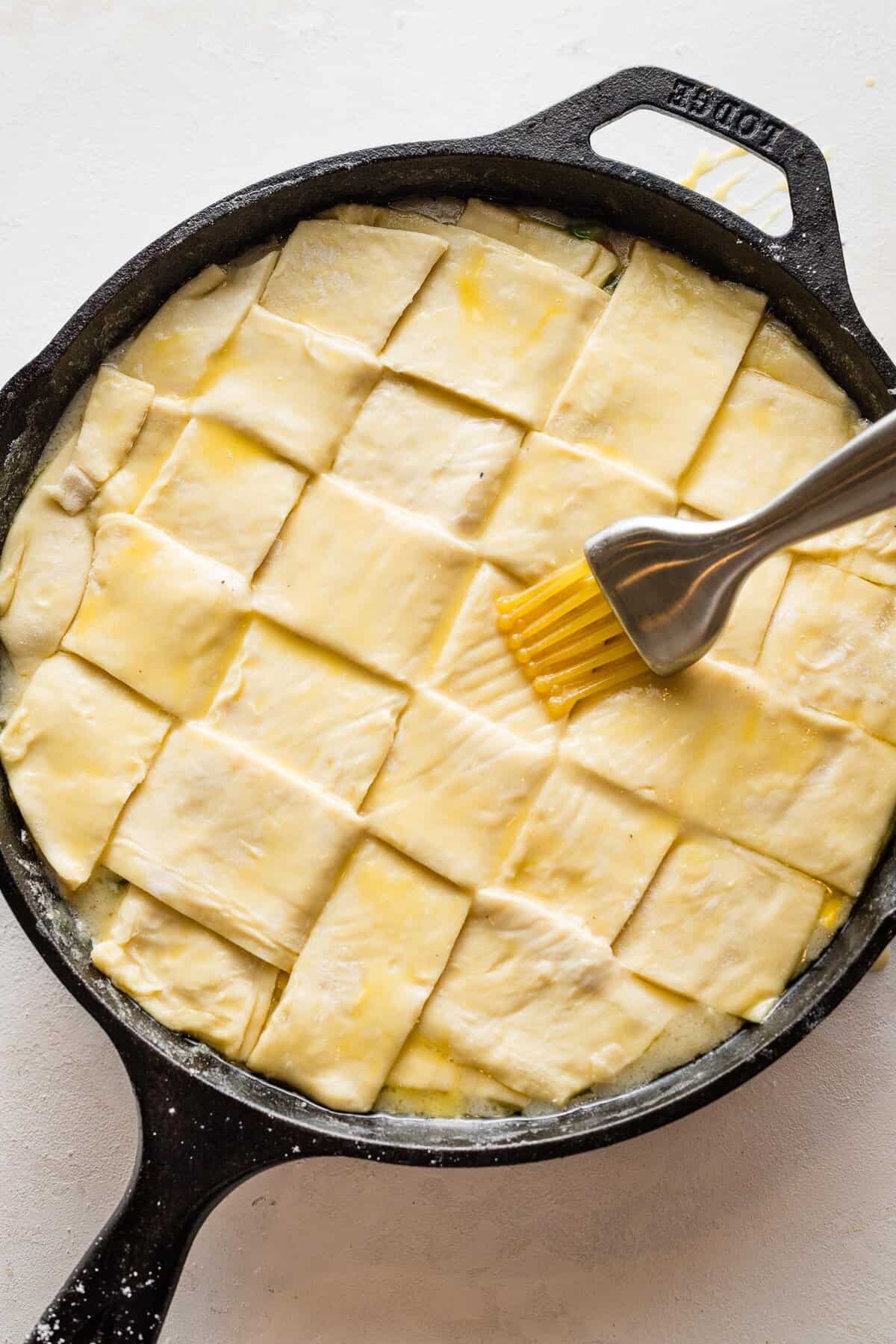 Butter being brushed over pastry of turkey pot pie.