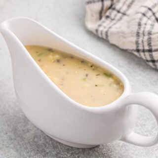 A white gravy boat filled with homemade turkey giblet gravy.