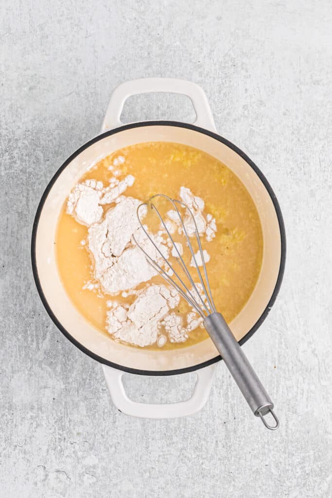 Flour and a whisk in a Dutch oven of giblet gravy base.