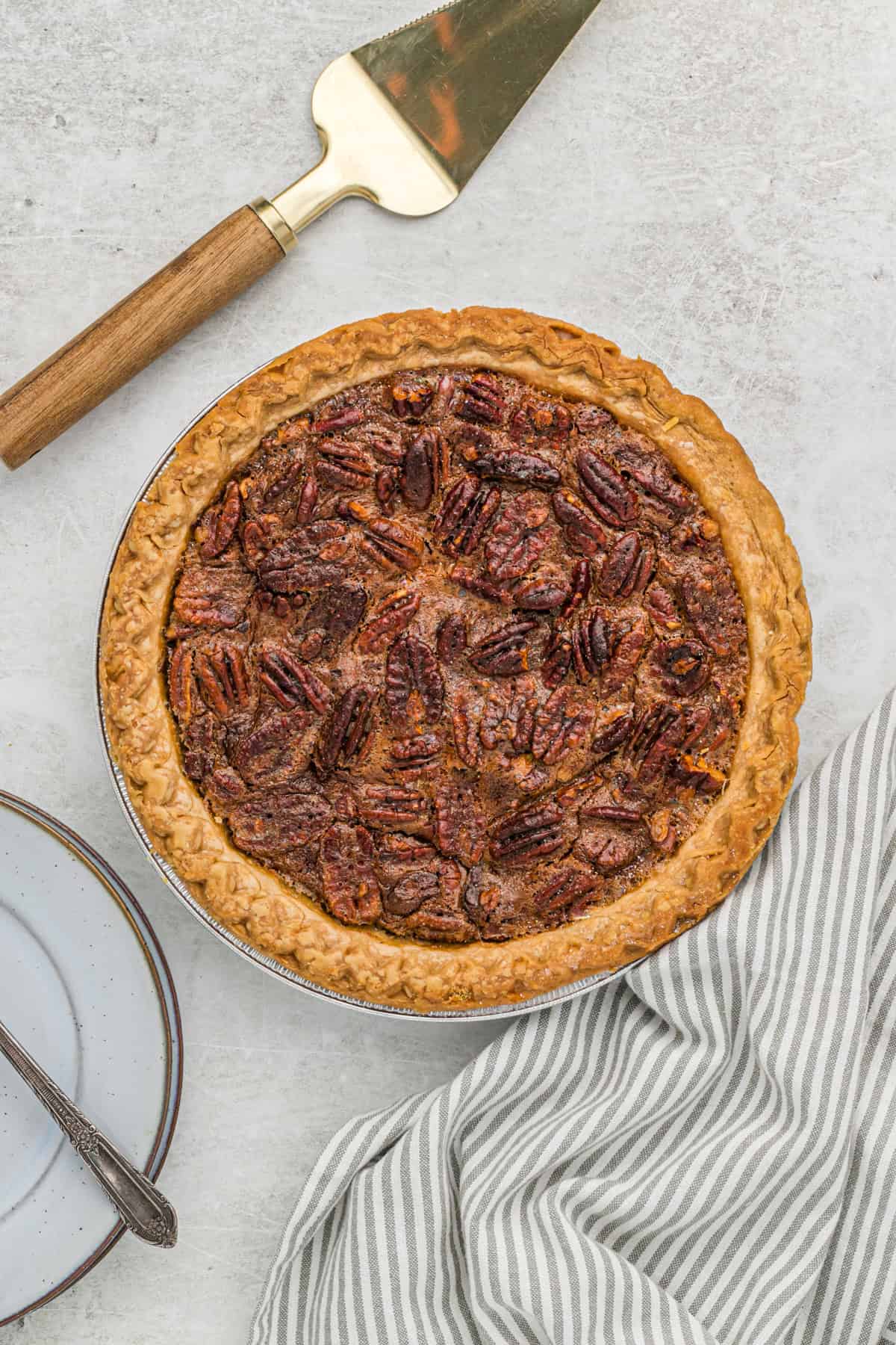 Southern pecan pie recipe out of the oven on countertop with napkin and server