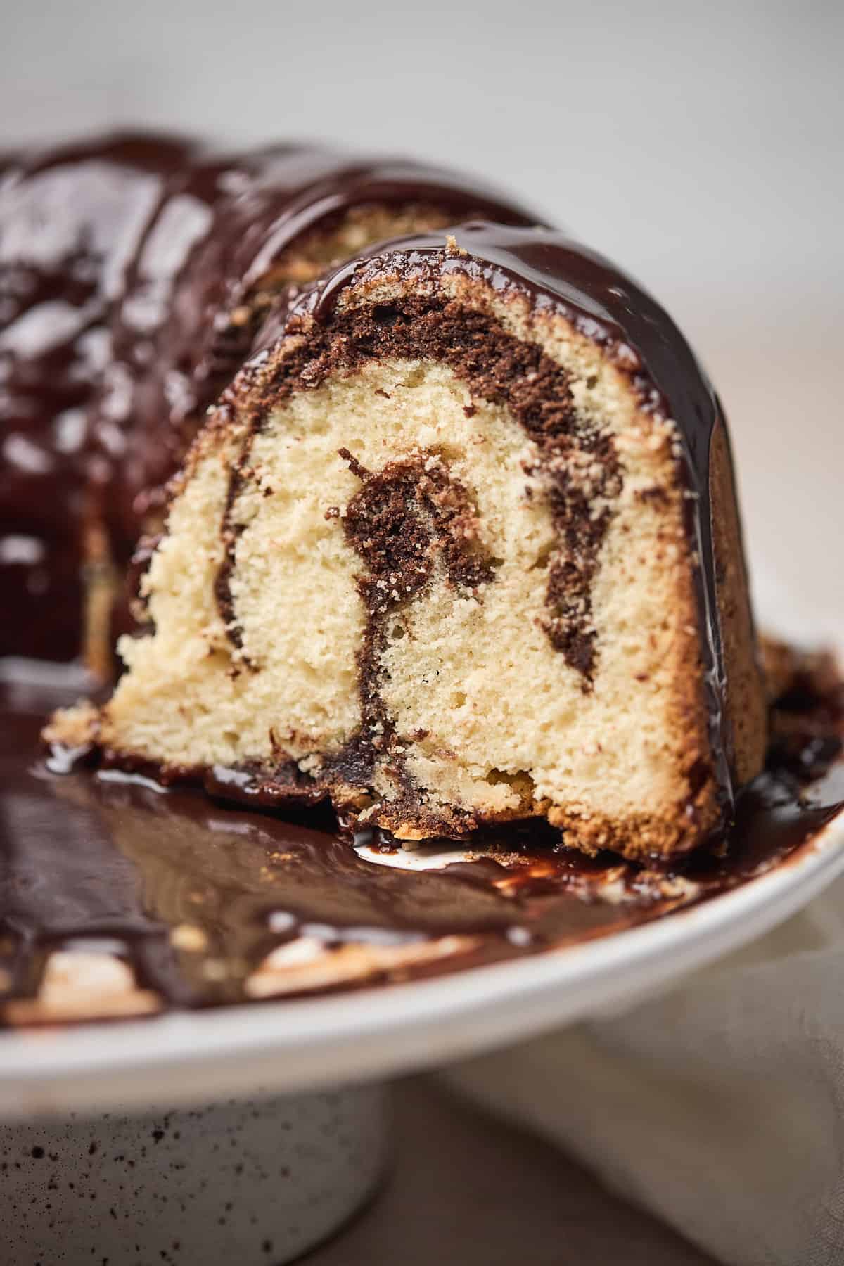 Brownie bundt cake on a platter with a portion cut to show a cross section of the cake on the inside.