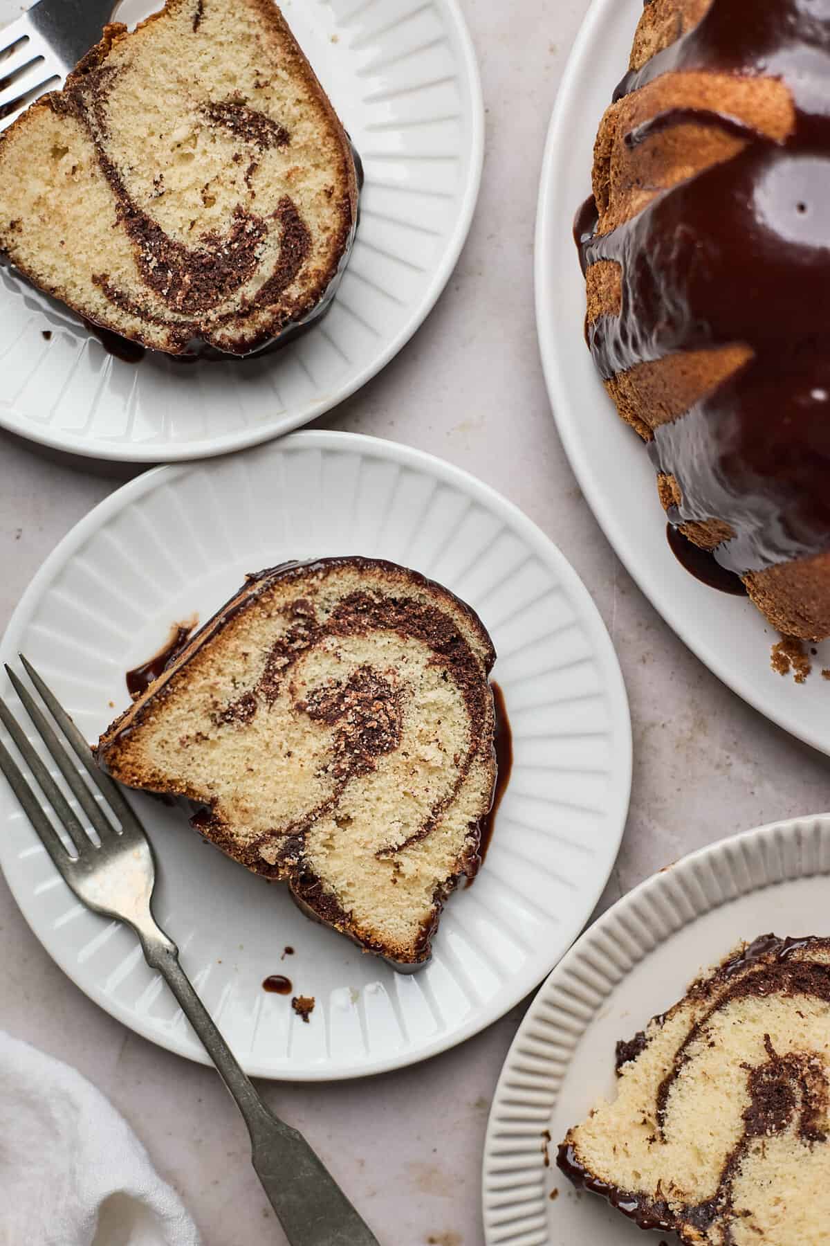 Slices of brownie swirl pound cake on little plates and the whole cake on the side of the image.