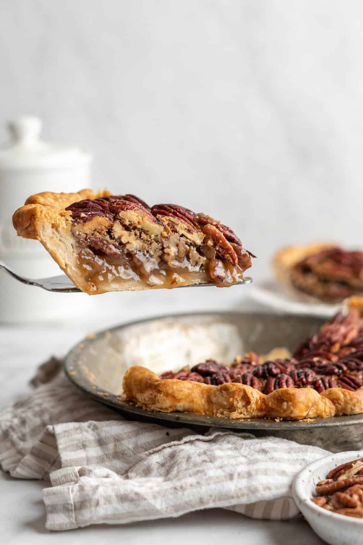 A slice of easy pecan pie being lifted up on a server on white background