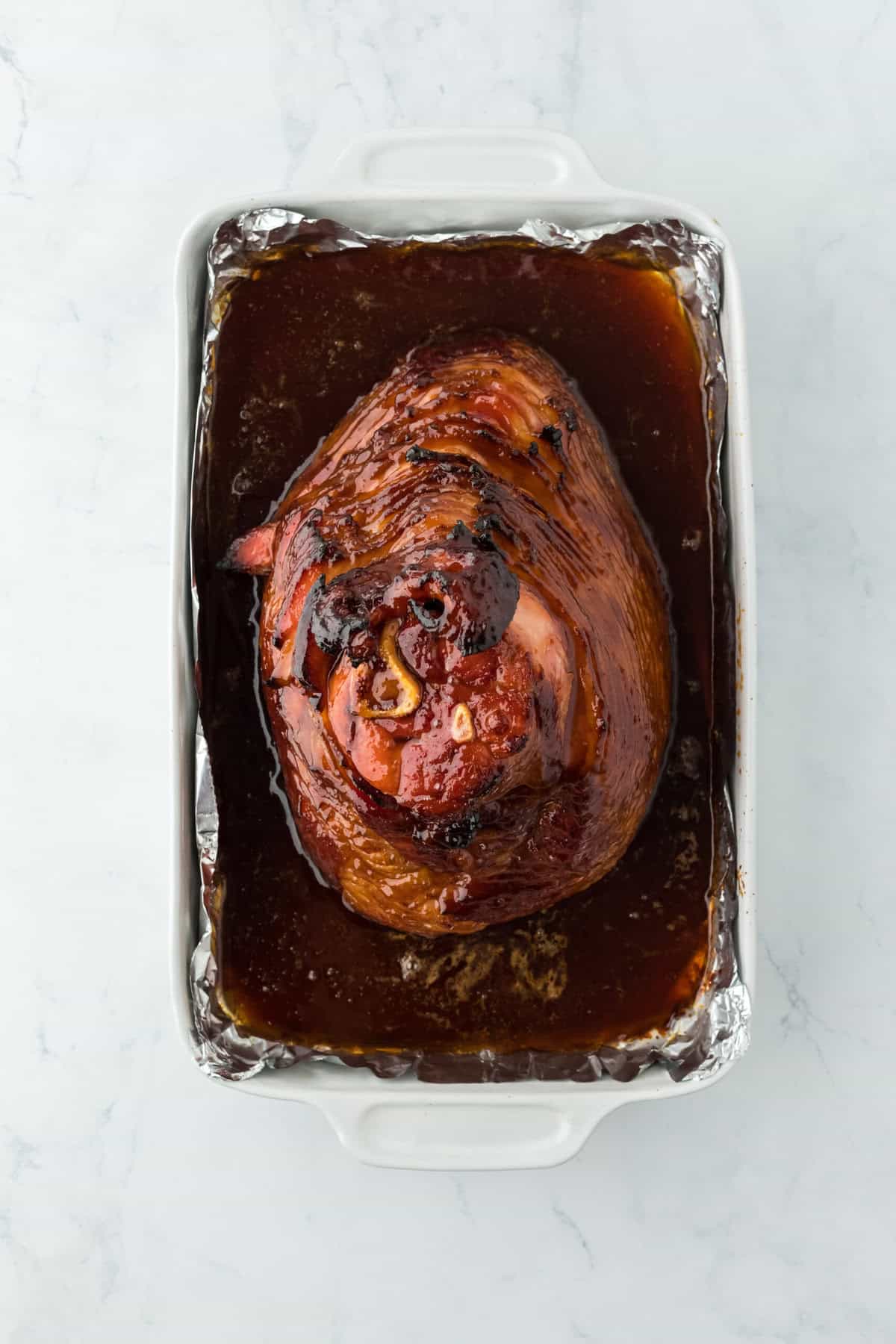 Glazed and baked ham on a foil lined baking sheet