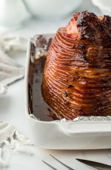 Perfectly roasted honey glazed ham recipe in foil in a white pan ready to enjoy