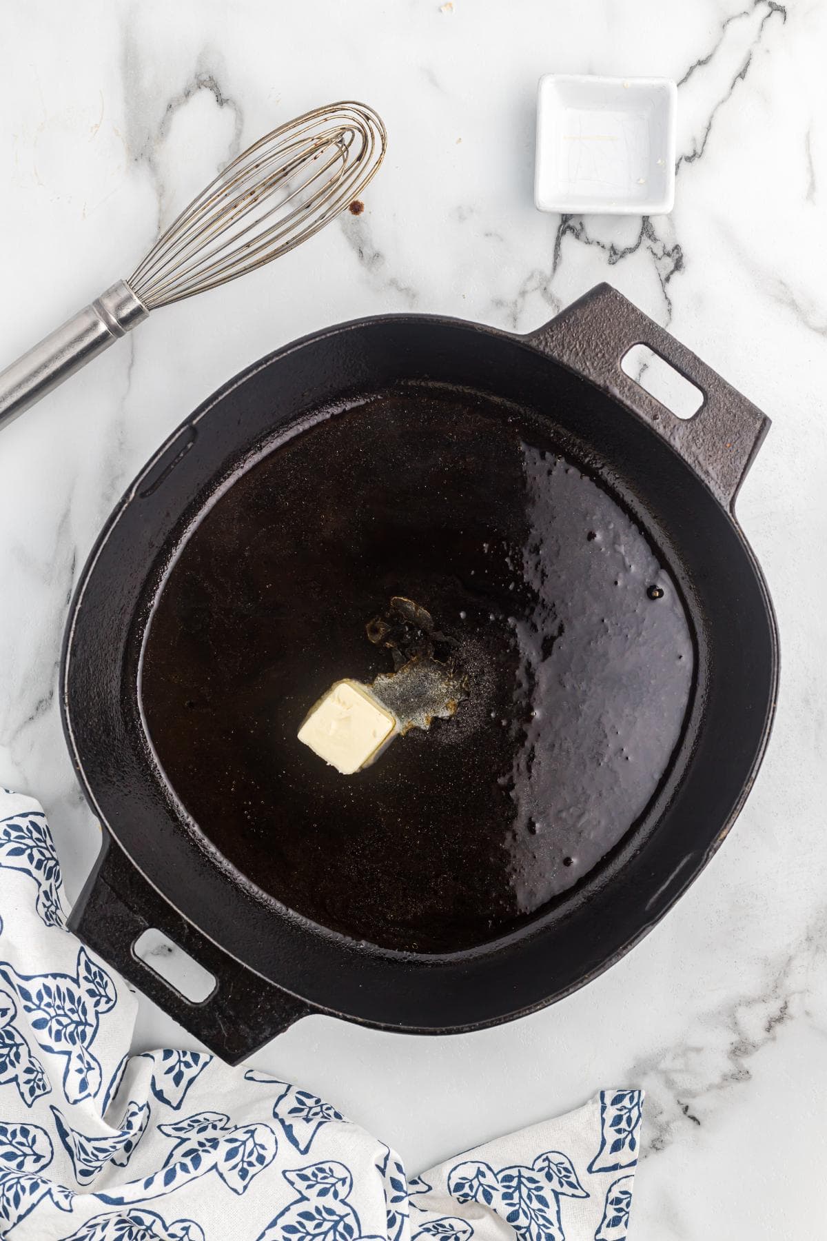 A pat of butter melting into the thickened red eye gravy inside the skillet