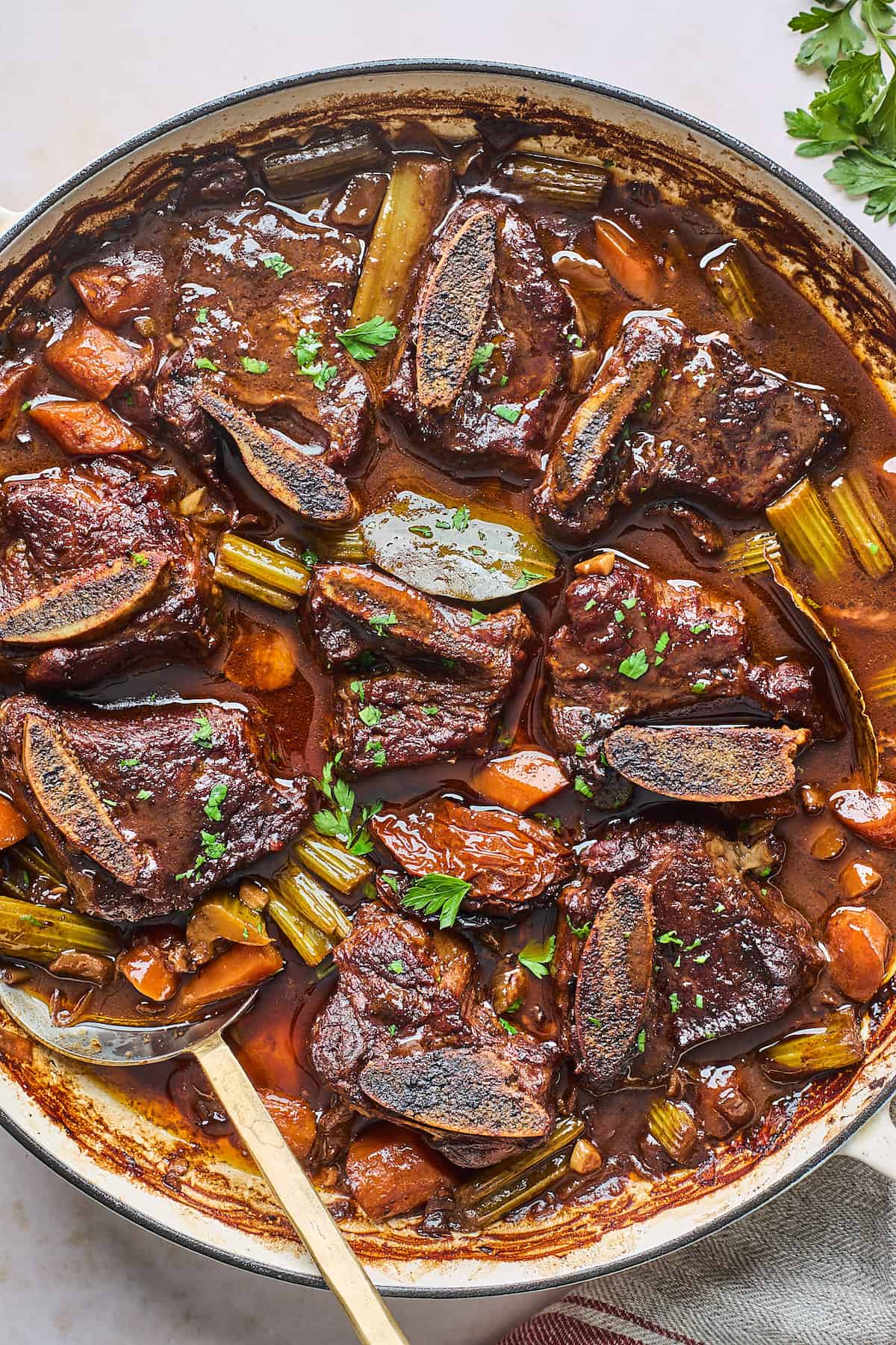 Braised beef short ribs with celery and carrots in a cast iron pot.