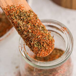 A wooden stick dipped into a jar of blackened seasoning.