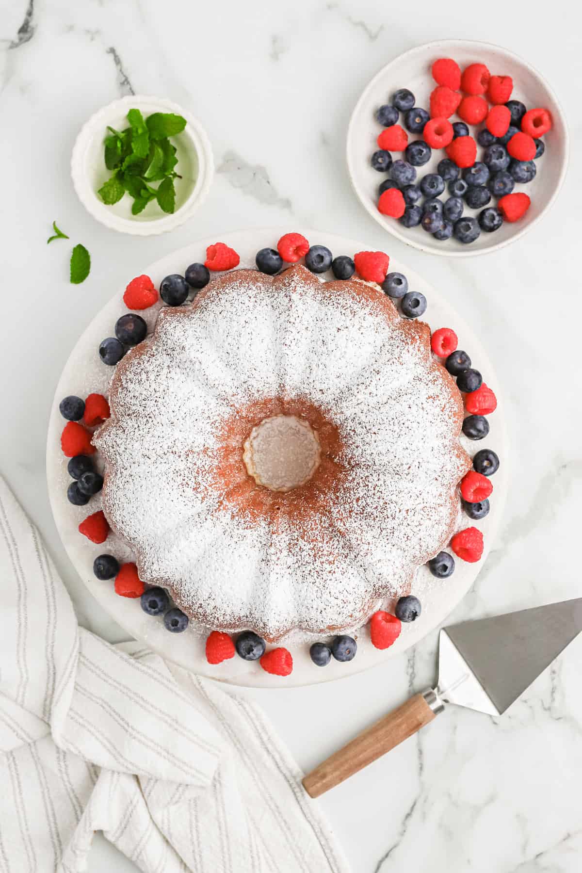 Pound cake with powdered sugar on top with berries surrounding it