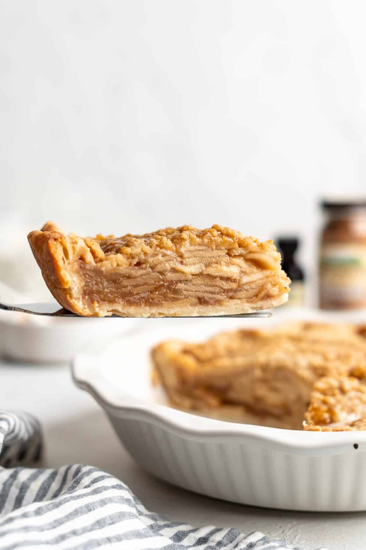 A slice of dutch apple pie recipe being raised from pie plate to serve