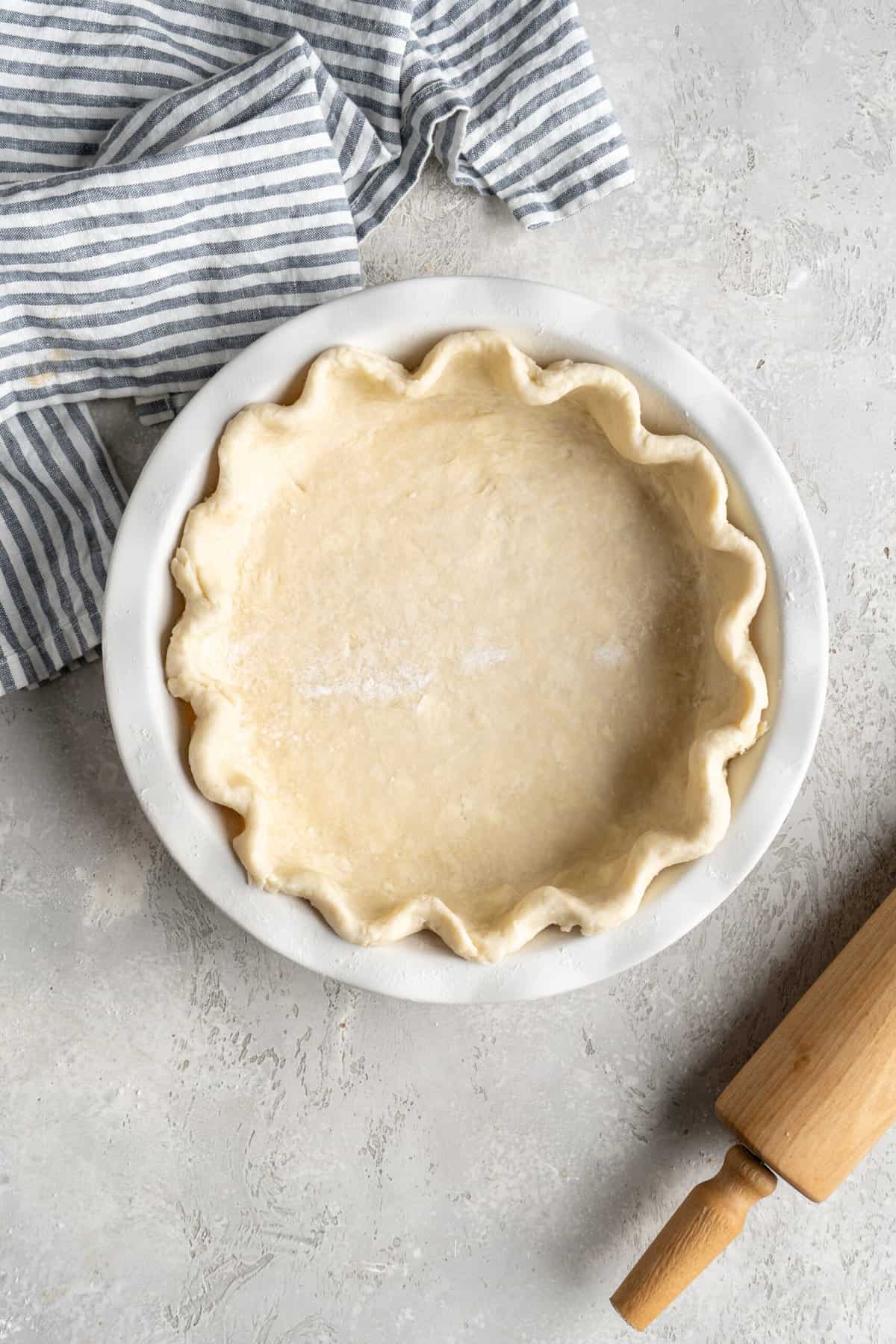 Pie dough crimped in white pie plate