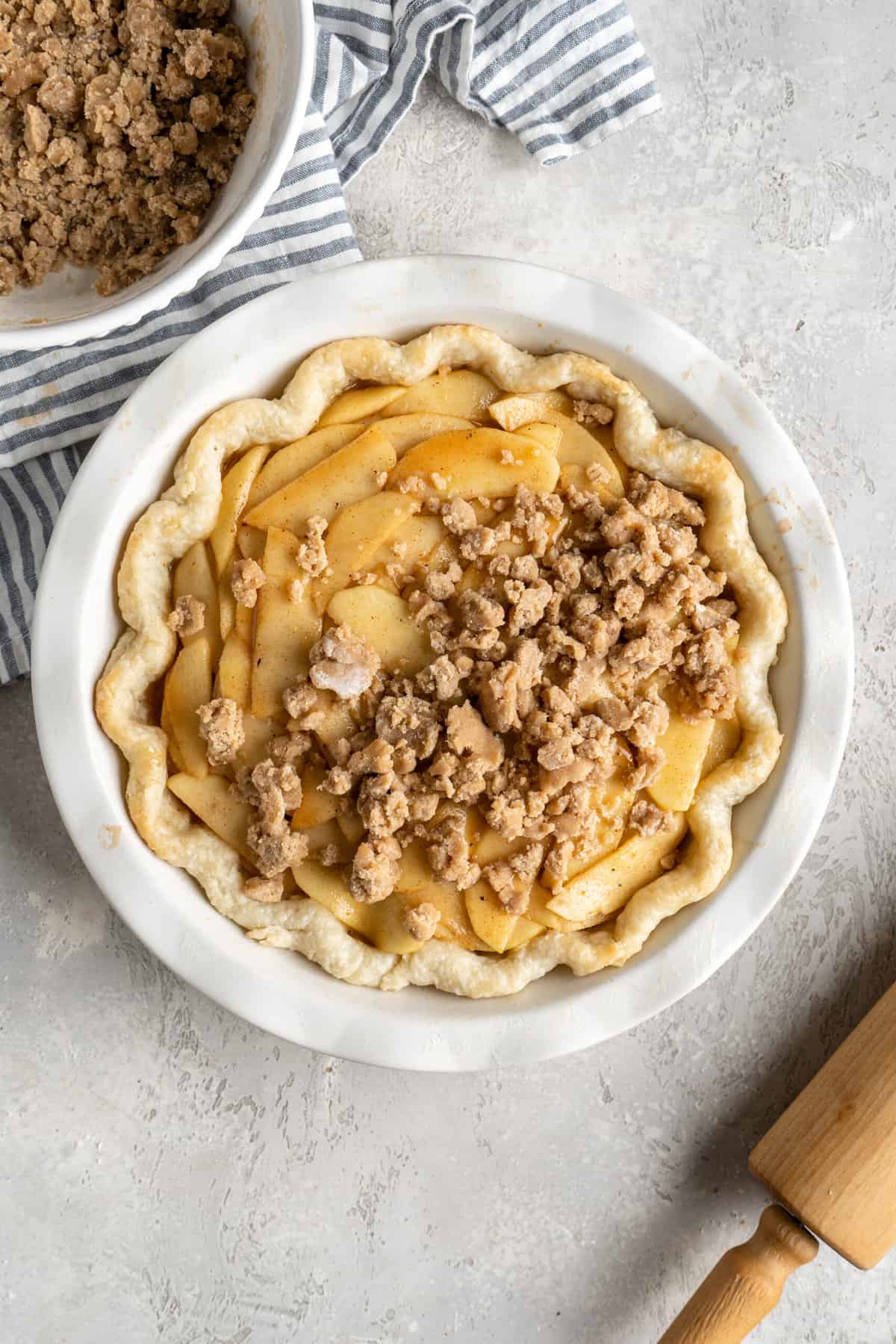 Crumble being sprinkled on top of a dutch apple pie