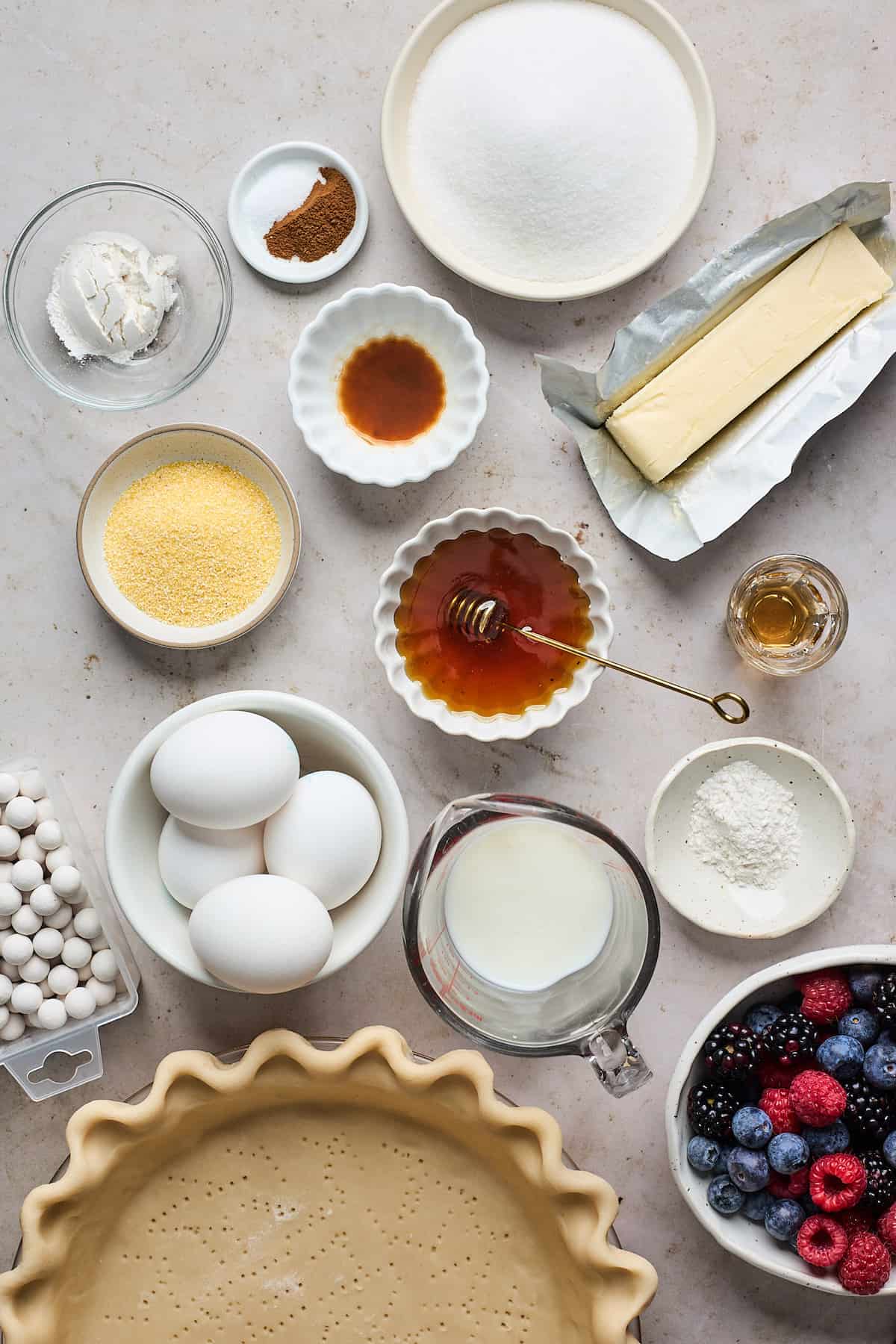 Ingredients to make honey cream pie in small bowls on a white surface.