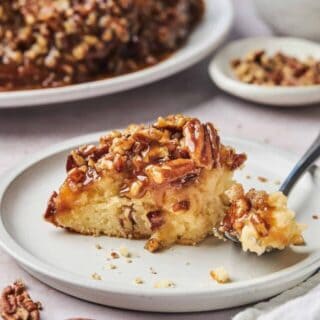 a slice of pecan upside down cake on a white plate with a fork