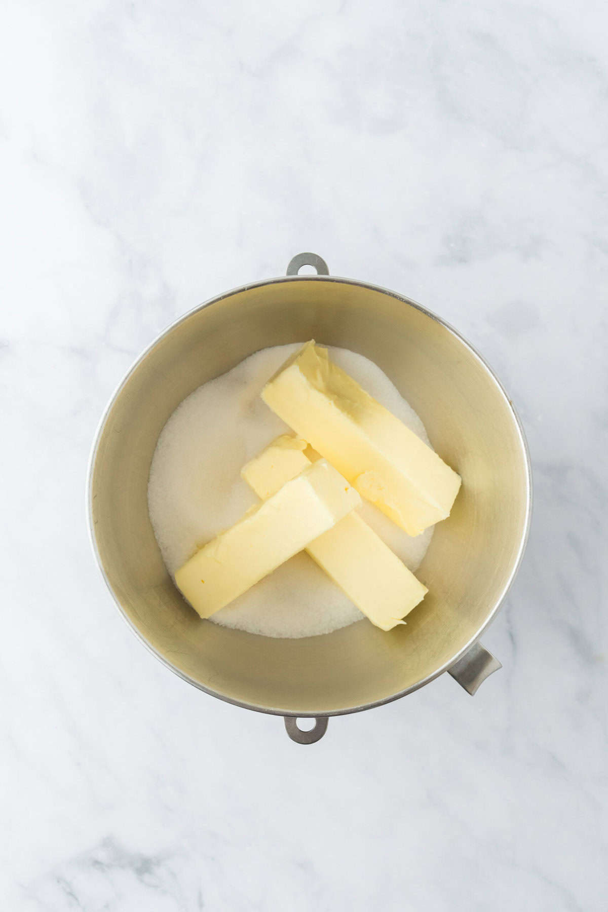 Butter and sugar in a stand mixer bowl on white countertop