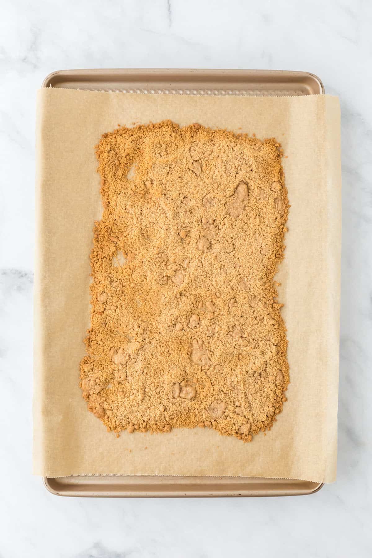 Baked streusel on a parchment lined baking sheet after baking.