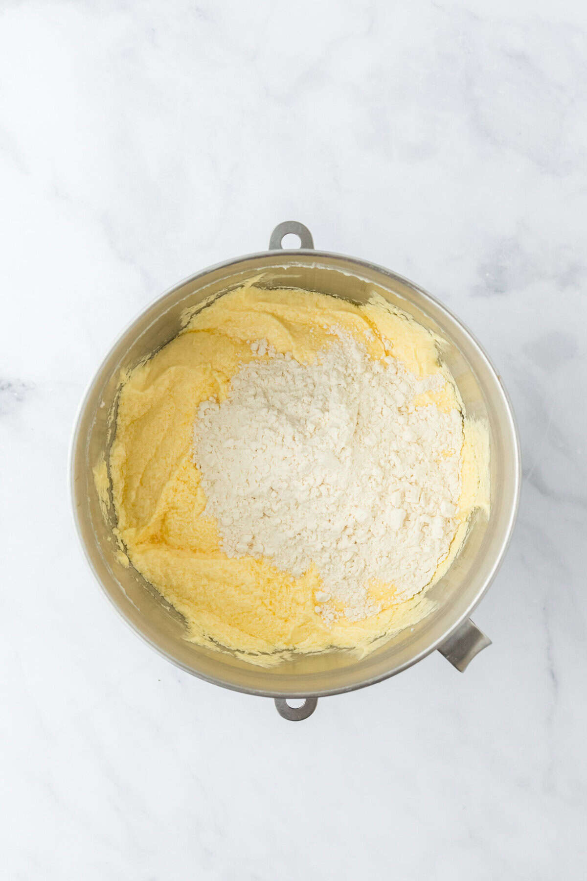 Flour mixture added to cake batter on white countertop