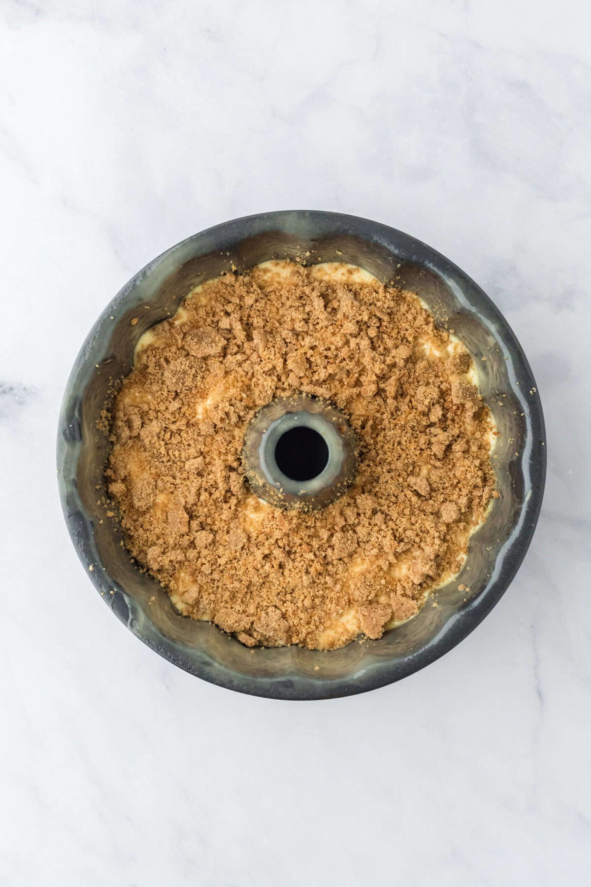 Streusel broken up and topped on cake batter in a bundt pan