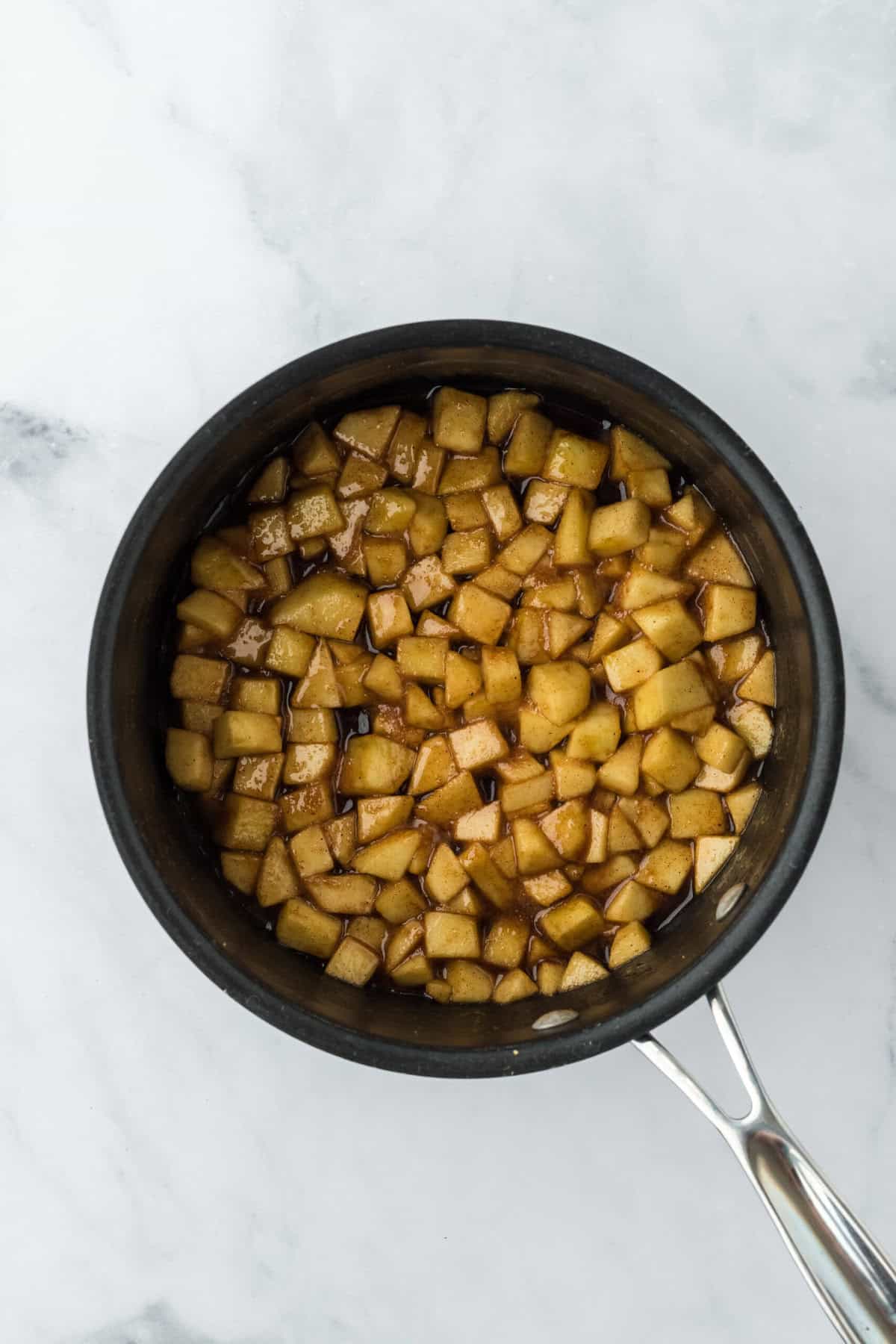 Apple filling for caramel apple pound cake in pot cooking on white background