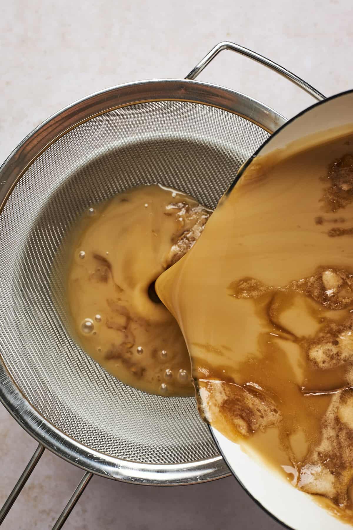 coconut caramel mixture being poured through a sieve. 