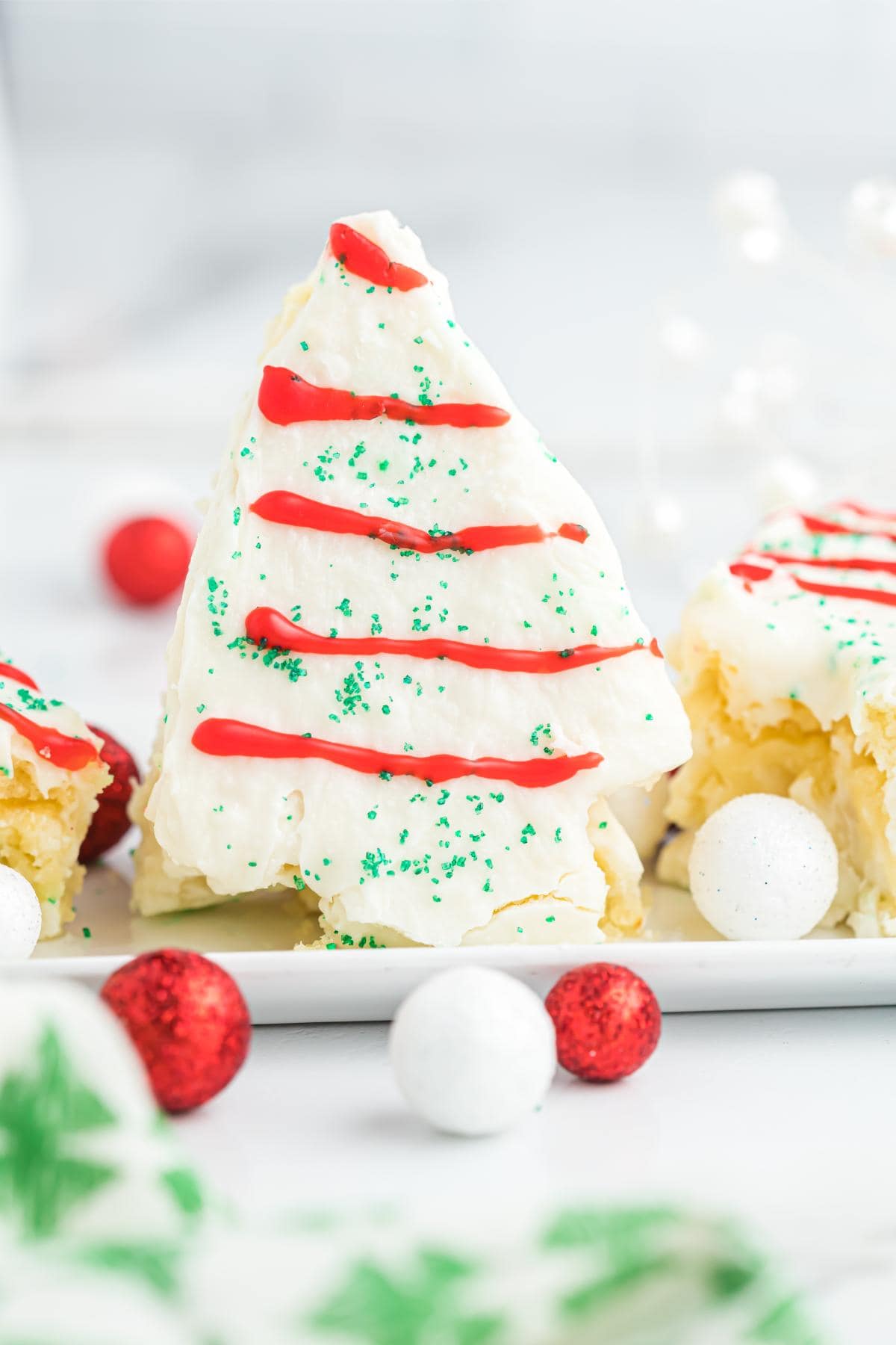 Closeup of a little debbie christmas tree cake standing next to red and white candies
