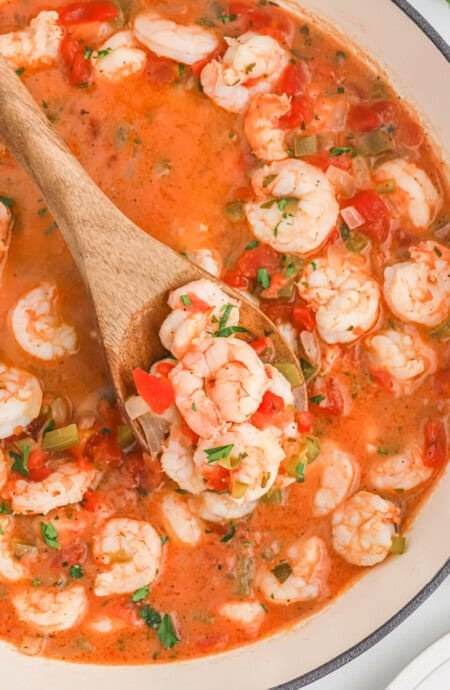 Shrimp in a tomato sauce on a wooden spoon